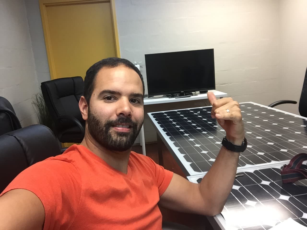 Miembro del equipo Kawara junto a paneles solares en el taller