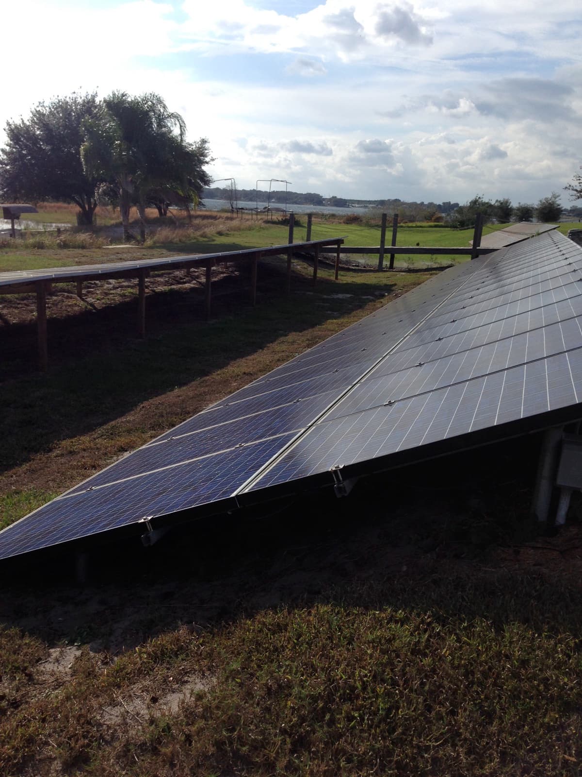 Arreglo de paneles solares montado a nivel de suelo en un terreno junto a un lago